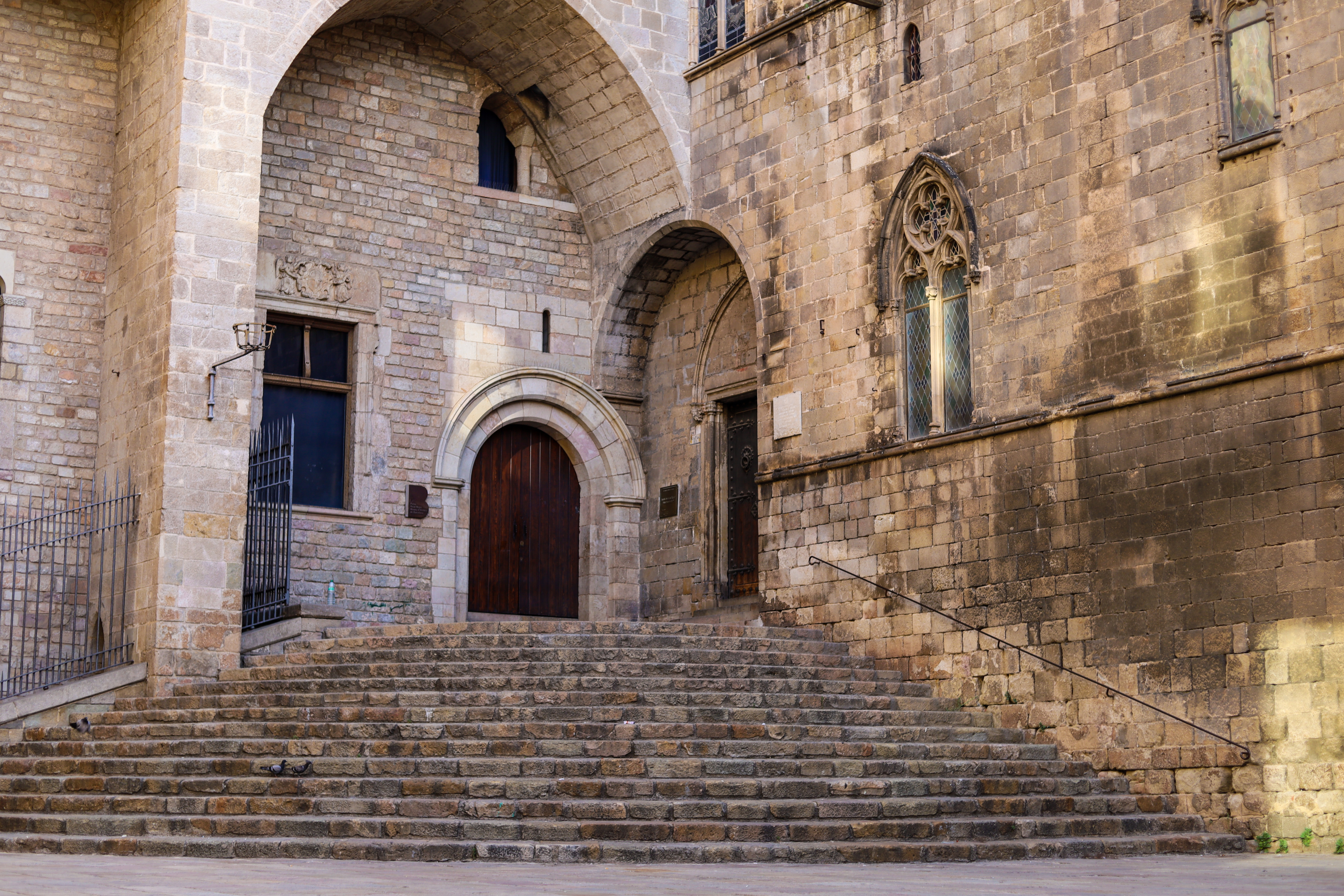 Ancient stone steps leading up to arched doorways in the Gothic Quarter